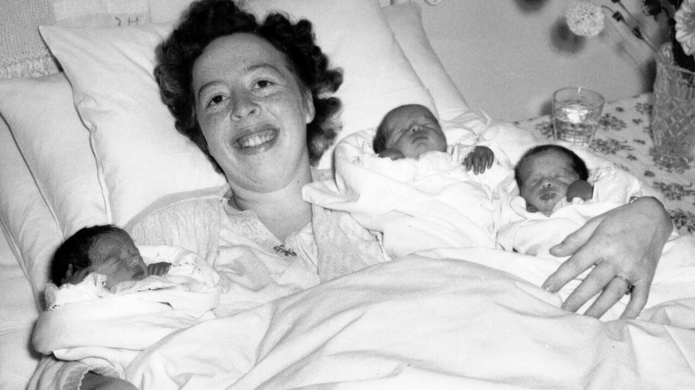 Bildet viser en nybakt mor med trillinger etter hjemmefødsel