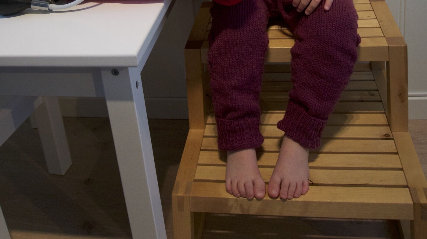 Blodtrykksmåling Bildet viser et barn som sitter på en krakk med støtte for beina og får blodtrykket sitt målt