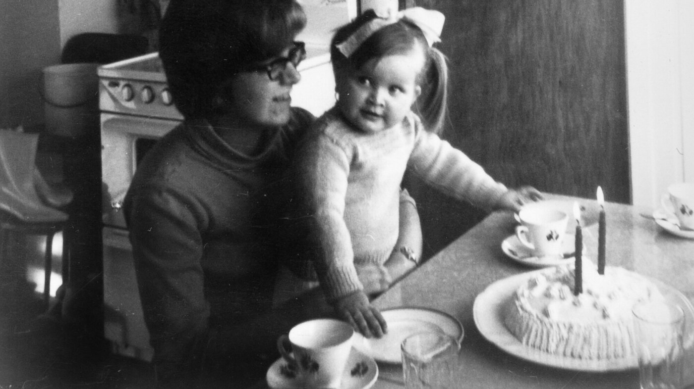 Bildet viser Karin Jonli som sitter på fanget til mamma med kake på bordet.