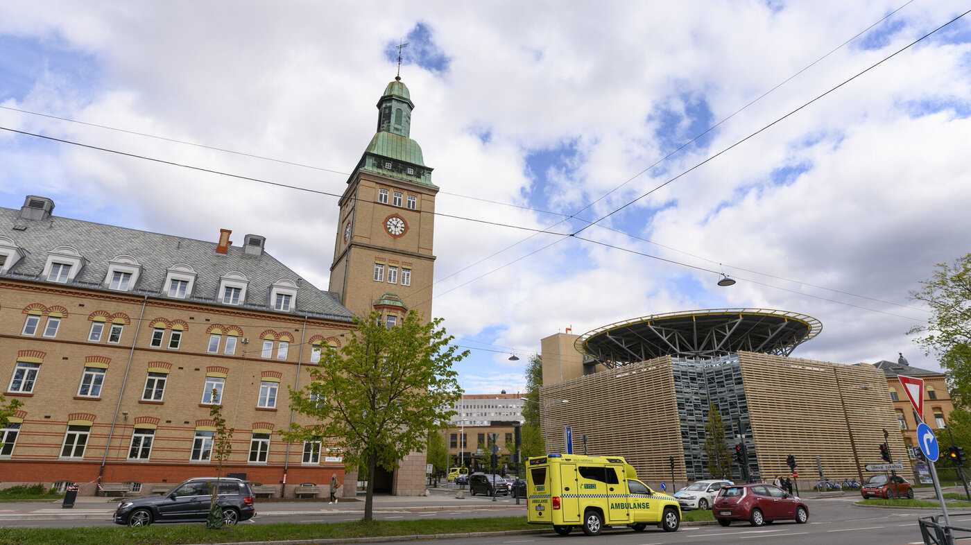 Gamle bygninger med helikopterlandingsplass fra Ullevål sykehus. Ambulanse og biler i forgrunnen.  