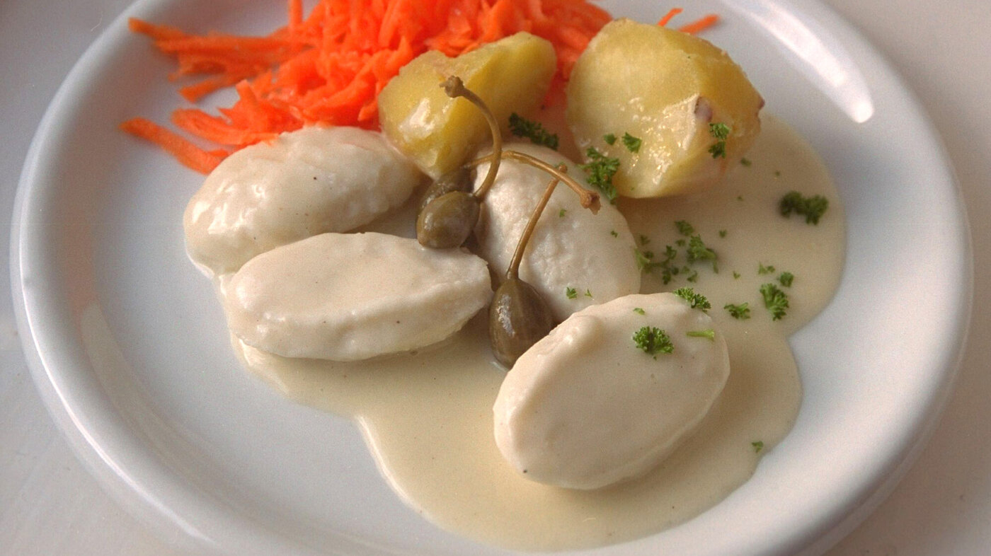 Bildet viser fiskeboller i hvit saus på en tallerken.