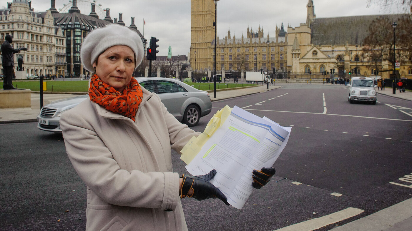 Bildet viser Julie Bailey som holder opp en rapport foran House of Parliament i London.