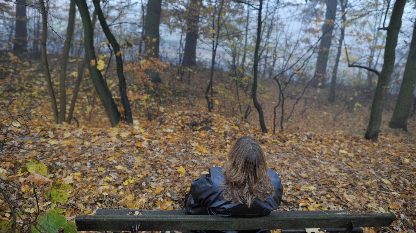 Kvinne sitter på benk i skogen. Illustrasjonsfoto: Frank May/NTB scanpix