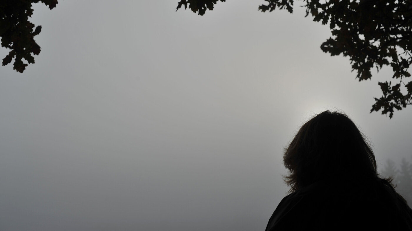 Bildet viser silhuetten av et menneske mot en grå himmel.