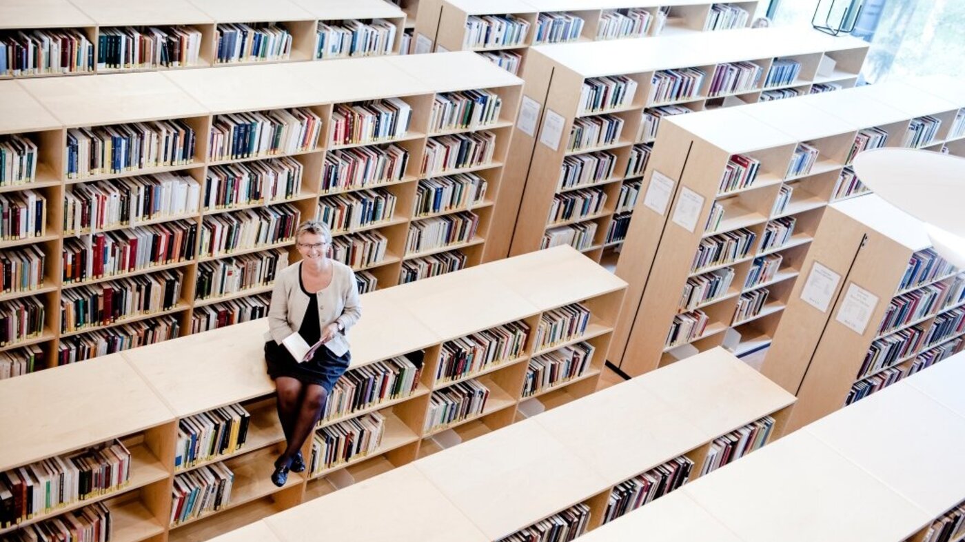 Bildet viser Kristin Heggen som sitter oppå en bokhylle.