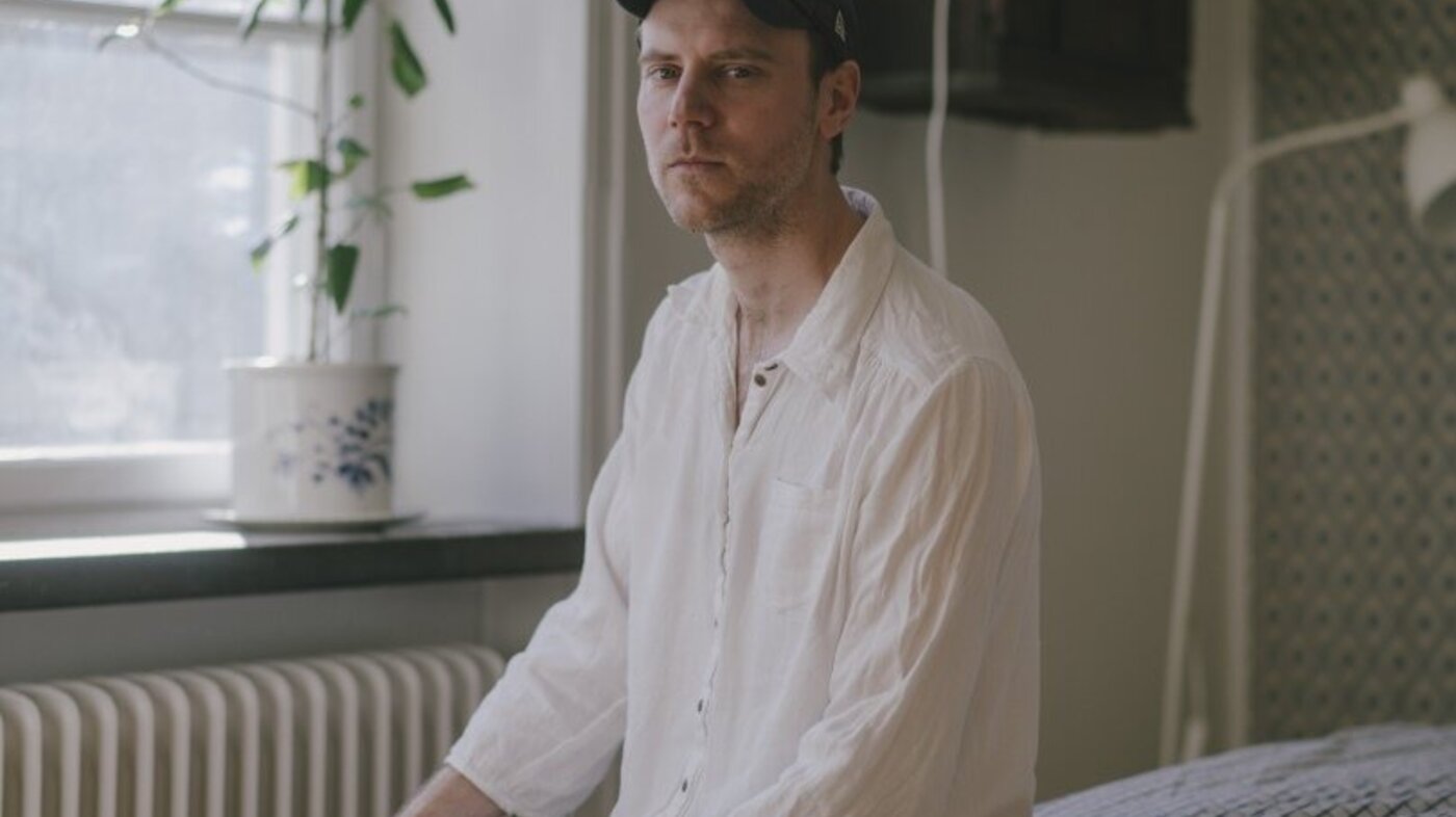 Bildet viser Tom Malmquist som sitter på en seng.