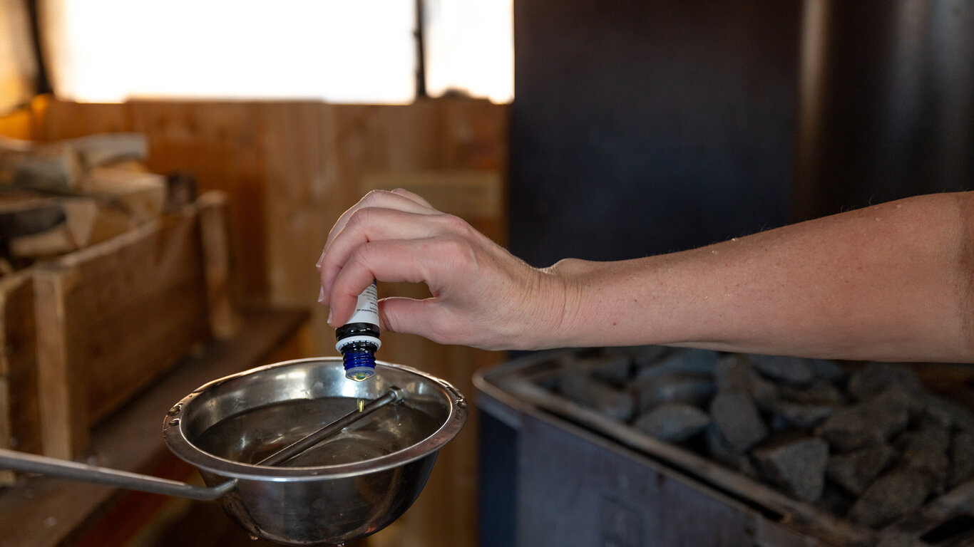 Bilde viser etteriskolje som helles i en badstue-skje.