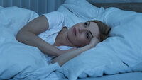 Bildet viser en dame som ligger i sengen og ikke får sove