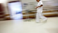 Bildet viser en sykepleier som går i en korridor.