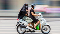 Bildet viser to på scooter som bruker munnbind.