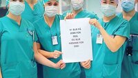 Bildet viser operasjonssykepleiere som holder opp et ark.