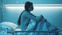 Ung, melankolsk kvinne i en sykehusseng