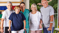 Bildet viser fire eldre personer som står sammen med en sykepleier. To av dem har krykker.