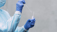 Bildet viser en helsearbeider med testpinne og prøveglass.