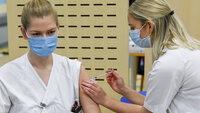 Bildet viser en sykepleier som blir vaksinert av en annen sykepleier.
