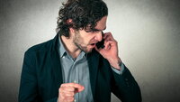 Bildet viser en sint mann som snakker i telefon
