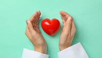 Bildet viser hendene til en sykepleier som holder rundt et hjerte