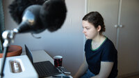 Bildet viser en ung jente som sitter foran PC-en på rommet sitt
