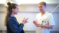 Bildet viser en døv kvinnelig pasient som snakker tegnspråk med en mannlig sykepleier