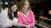 To kvinnelige sykepleiere leser en lommefolder.