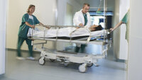 Pasient blir flyttet i seng på et sykehus
