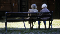 Bildet viser to eldre kvinner som sitter på en benk