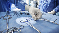 Bildet viser hånd som holder kirurgiske instrumenter.