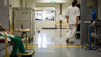 Bildet viser en sykepleier og en pasient i en sykehuskorridor