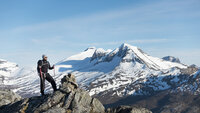 Bildet viser en mannlig turgåer som står på en fjelltopp
