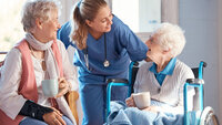 Bildet viser en sykepleier som snakker med to eldre beboere på et sykehjem