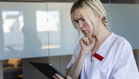 Bildet viser en kvinnelig sykepleier som bruker et nettbrett