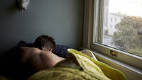 Bildet viser en ung mann som ligger i sengen