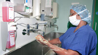The photo shows a surgical nurse washing her hands before surgery