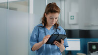 Bildet viser en sykepleier som skriver på et nettbrett.