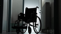 Bilde viser en tom rullestol på et pasientrom i motlys