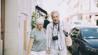 Bildet viser et eldre par som går i en by