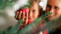 Bildet viser en liten jente og hennes mor som pynter juletre