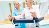 Sykepleier og eldre kvinne med gåstol