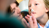 Bildet viser ei jente som får deksmedetomidin i form av nesespray før operasjon