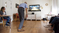 Bildet viser en eldre mann som spiller bowling på storskjerm ved hjelp av Kinect.