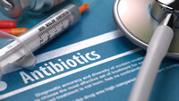 Bilde av sprøyte og antibiotika som ligger på en bakgrunn hvor det står "antibiotika"