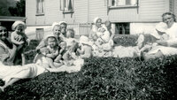 Historisk, gammelt bilde av sykepleiere med små barn på gresset utenfor Bergen kommunale mødrehjem.