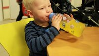 Sebastian drikker gul saft fra flaske.