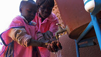 Voksen hjelper barn med håndvask