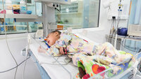 Bildet viser en baby med hjertefeil som ligger i kuvøse på sykehus