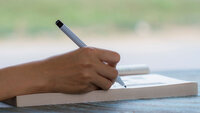 Bildet viser hånden til en som skriver dagbok. Hånden holder en penn.