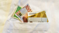 Penger og bankkort i lommen på en sykepleieruniform