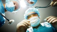 Tre kirurger kikker ned på en pasient