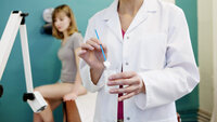 Bildet viser en lege med utstyr til celleprøve, en ung jente sitter i bakgrunnen.