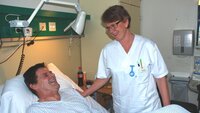Bildet viser ALS-pasient Odd Arne Bøe i en sykehusseng. Spesialsykepleier Tone Lahaug Nilsen står ved siden av.